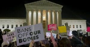 A group of people holding signs in front of the supreme court.