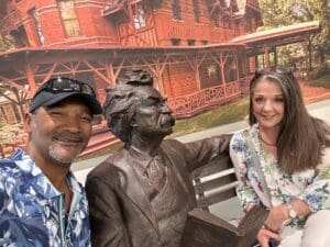 A man and woman pose next to a statue of albert einstein.