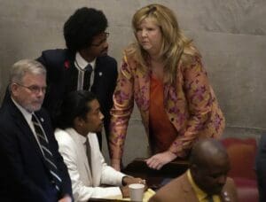 A woman in a suit and tie is talking to a man in a suit.