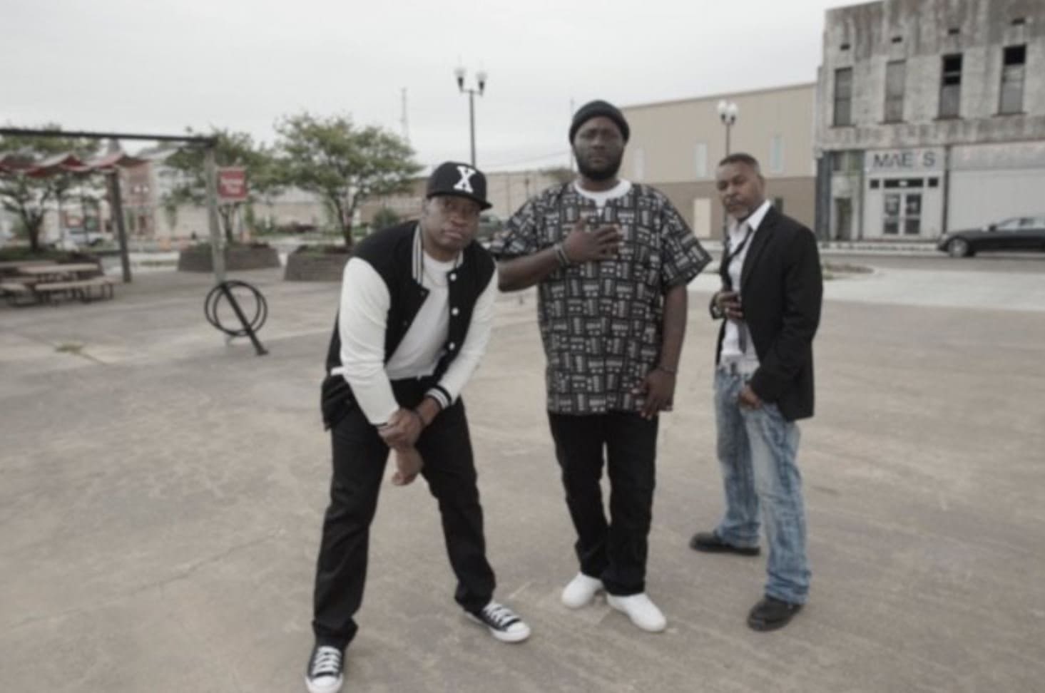 Three men posing together on a city street.