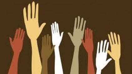 Raised hands of different skin tones.