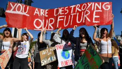 Protestors hold signs about climate change.