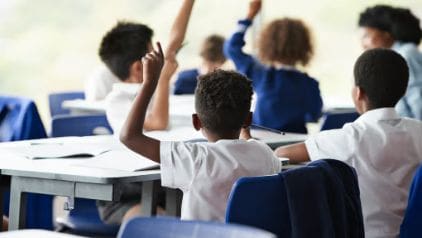 Students in a classroom with raised hands.