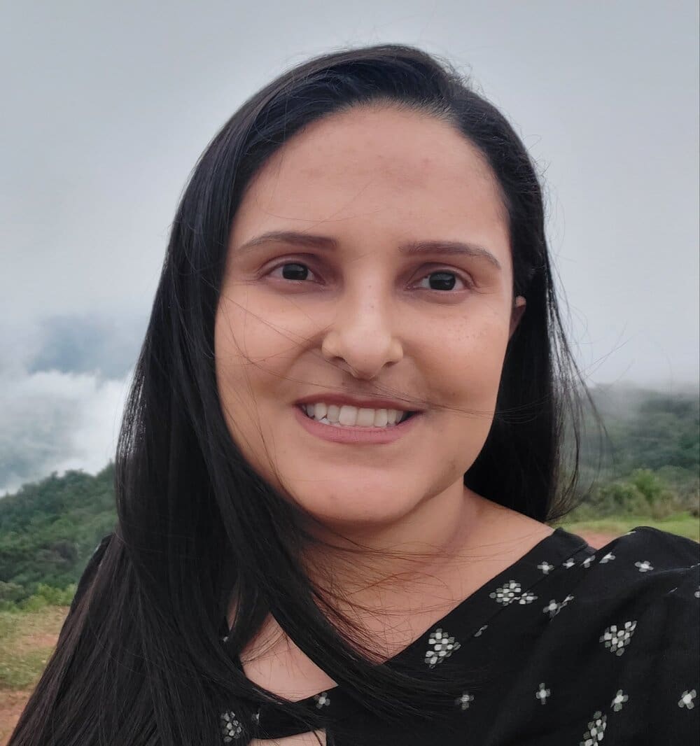 Woman with long black hair smiling outdoors.