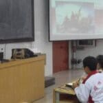 A woman lectures students in a classroom.