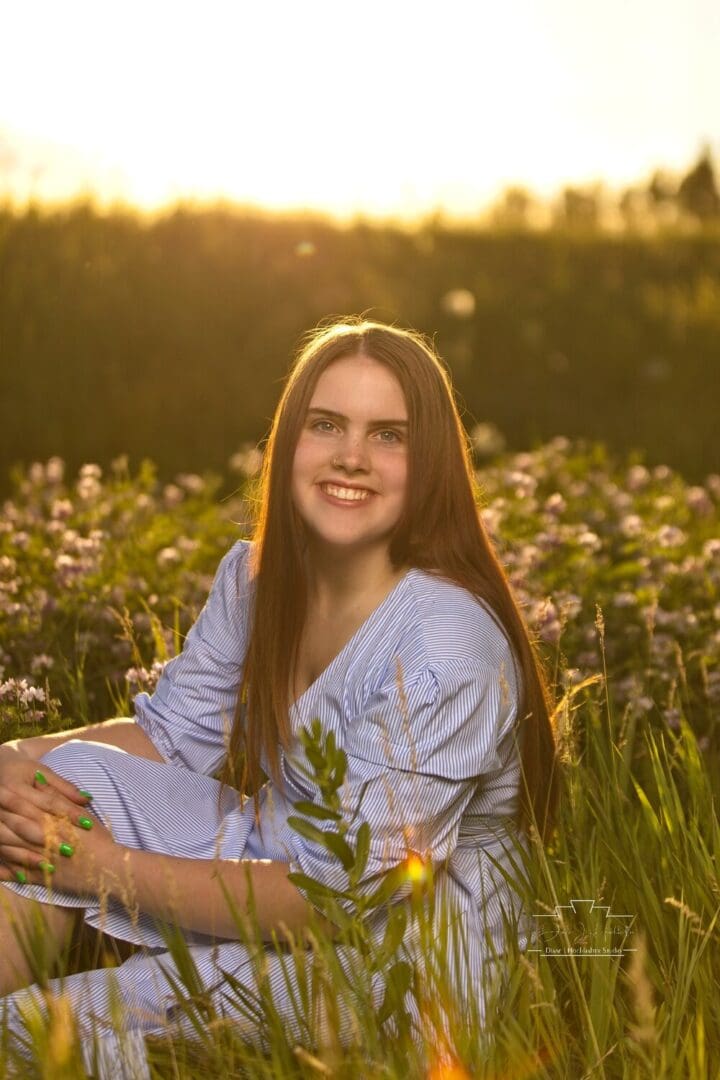 Smiling woman in a blue dress in a field.