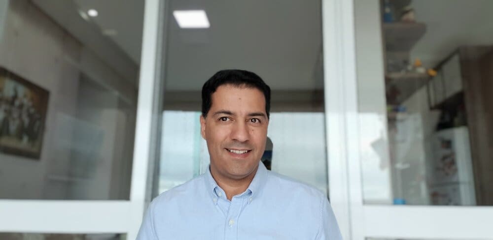 Man in blue shirt smiling indoors.