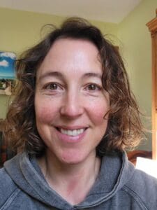 Woman with curly brown hair smiling.