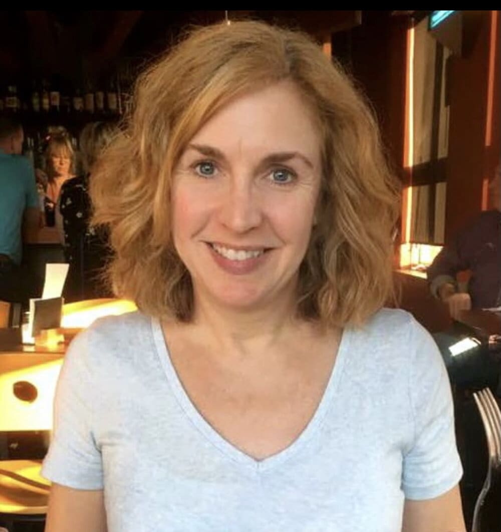 Woman with blonde hair smiling in a bar.