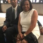 An older couple sitting together, smiling.