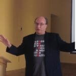 Man giving presentation with "America" words on shirt.