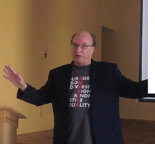 Man giving presentation with "America" words on shirt.