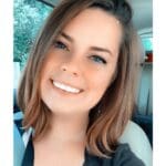 Smiling woman with brown hair in a car.