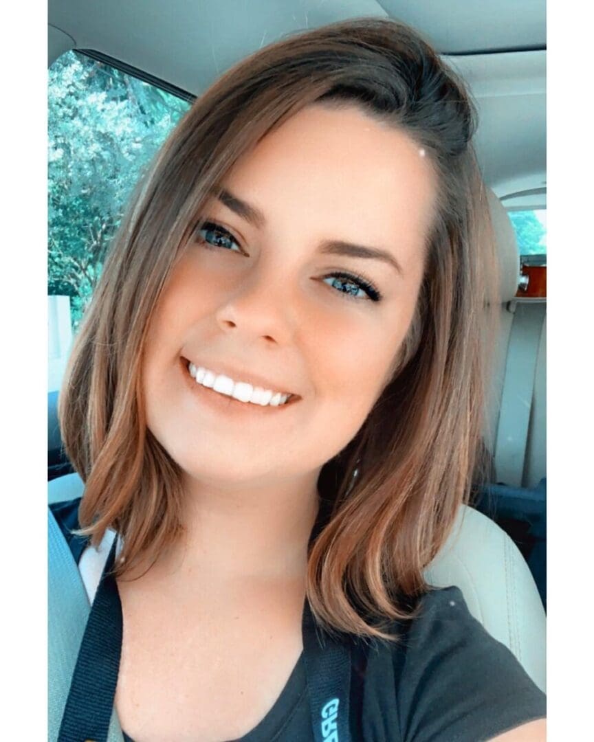 Smiling woman with brown hair in a car.