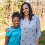 Smiling mother and daughter in a park.