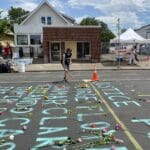 Flowers on street with chalk message.