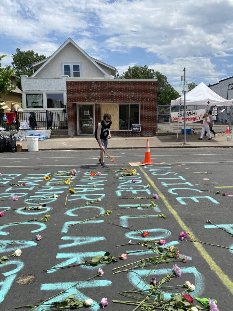 Flowers on street with chalk message.