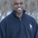 Smiling man in a blue sweater.