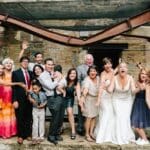 Wedding party posing under a rusty beam.