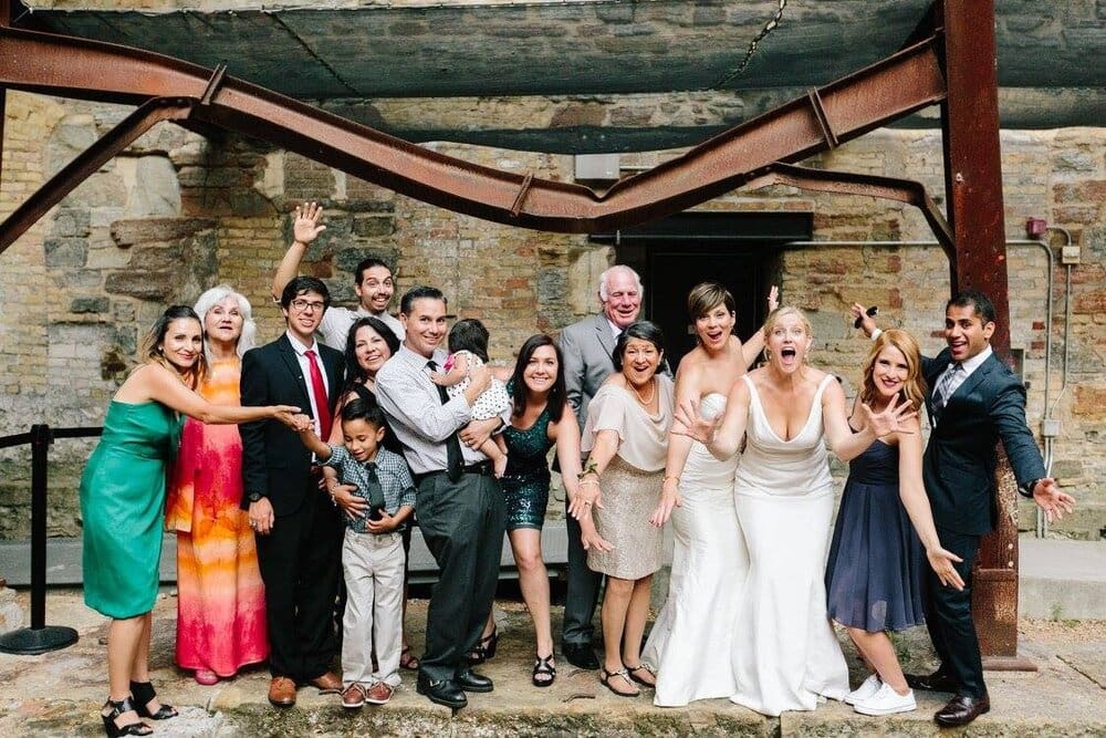 Wedding party posing under a rusty beam.