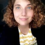 Smiling woman with curly hair in a striped shirt.