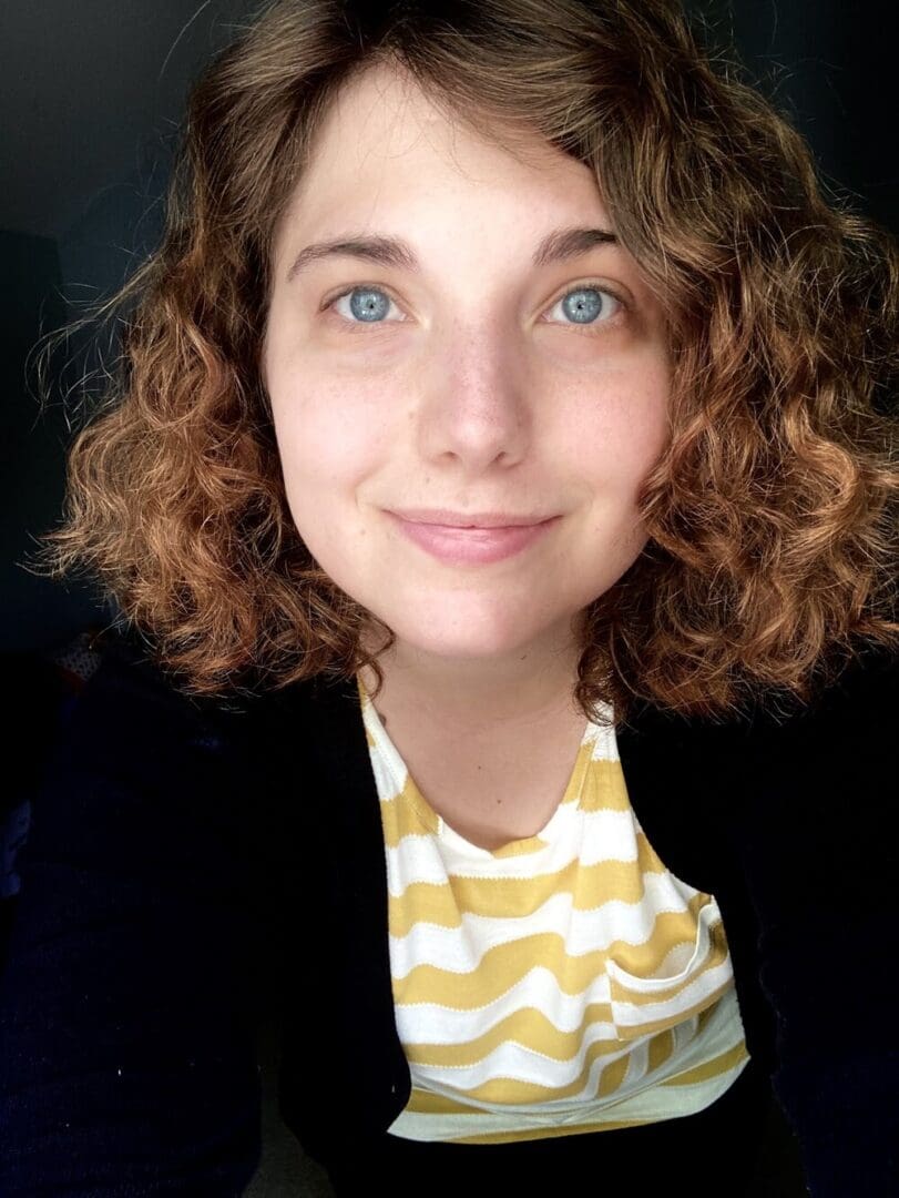 Smiling woman with curly hair in a striped shirt.