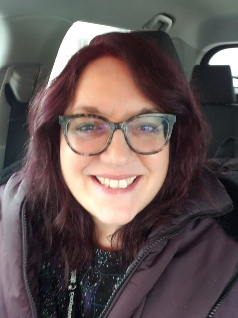 Smiling woman with glasses in a car.