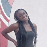 Smiling woman with long braids in a tank top.