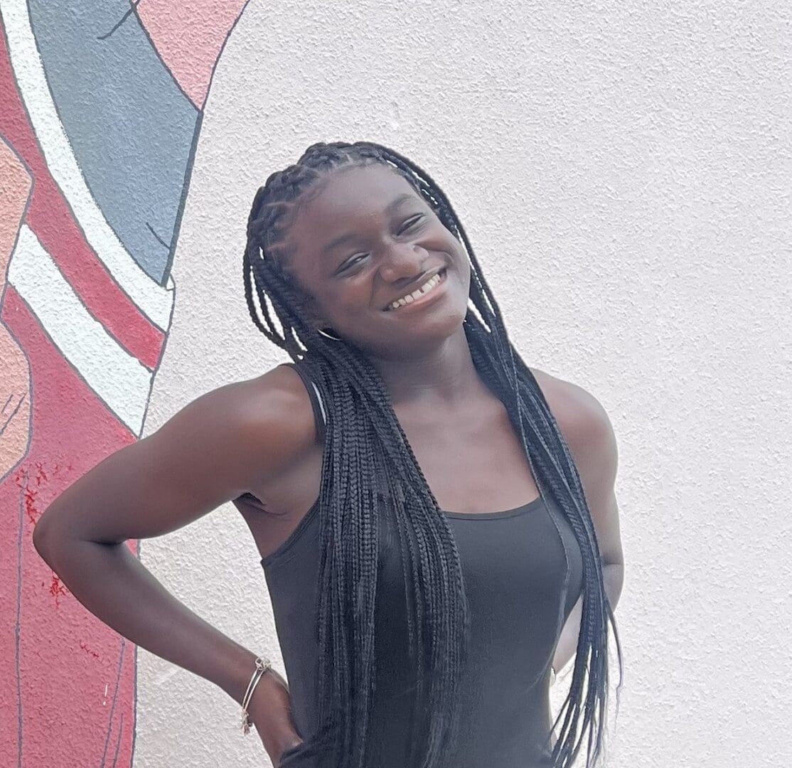 Smiling woman with long braids in a tank top.