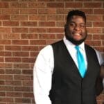 Man in a black vest and blue tie.