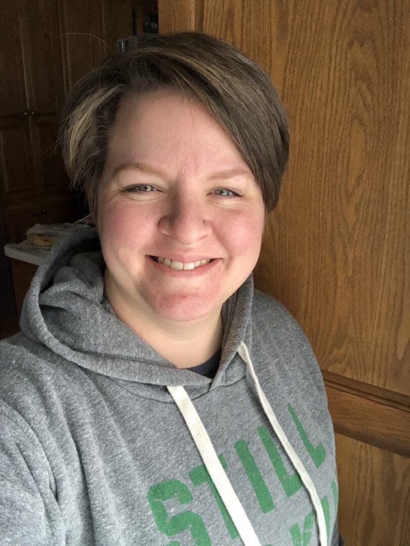 Smiling woman in a gray hoodie.