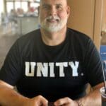 Man wearing a unity shirt, holding a phone.