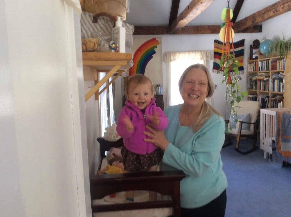 A woman holding a baby in a pink jacket.