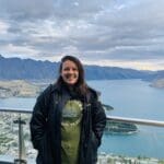 Woman smiling on a mountain overlooking a lake.