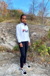 Young woman in Fila sweater and Vans shoes.