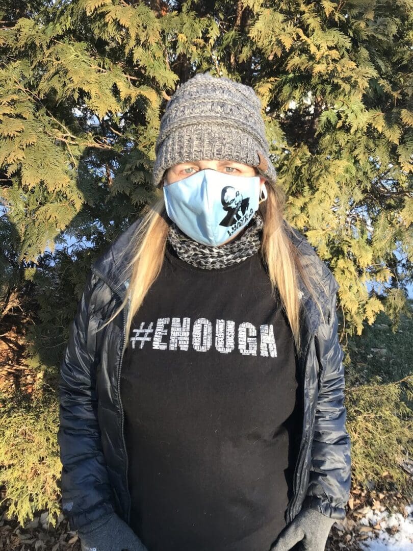 Woman wearing a #ENOUGH shirt and a mask.