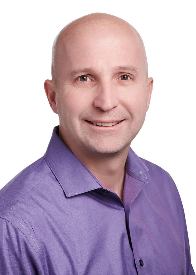 Smiling man in a purple shirt.