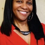 Woman smiling in red dress with lanyard.