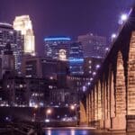 Stone bridge and city skyline at night.