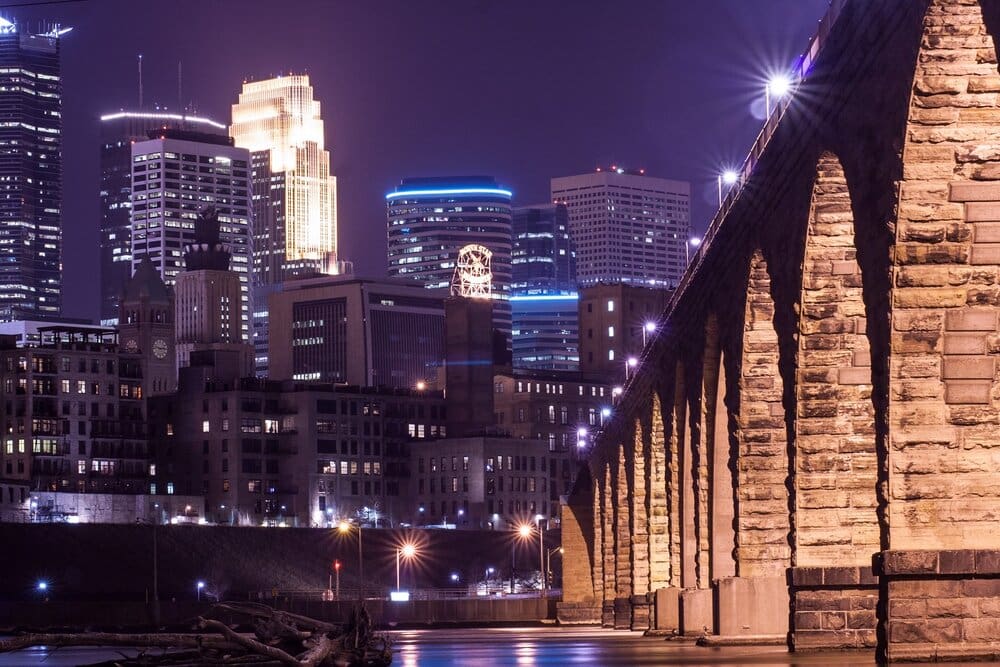 Stone bridge and city skyline at night.