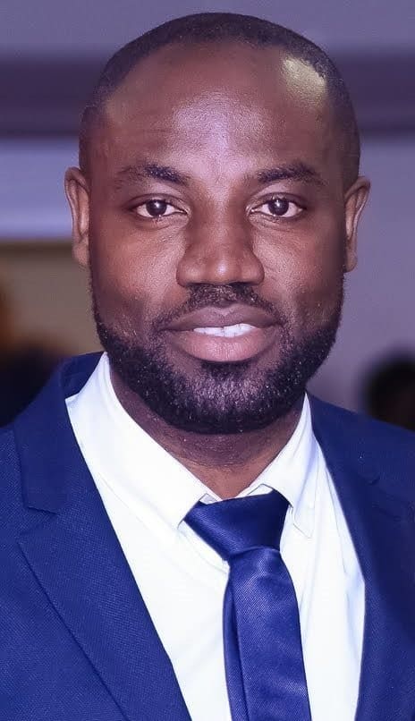 Man in a blue suit and tie smiling.