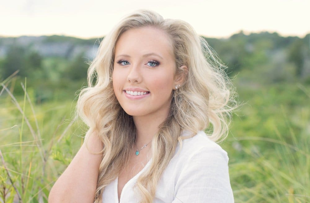 Smiling woman with blonde hair in a field.