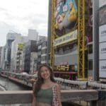 Woman in green top near Japanese Ferris wheel.