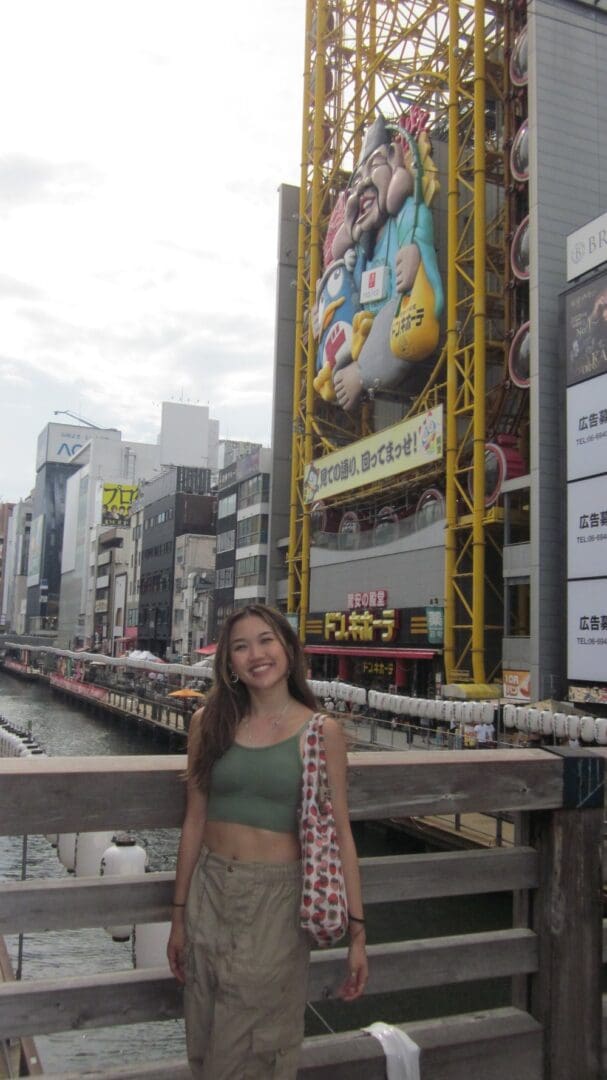 Woman in green top near Japanese Ferris wheel.