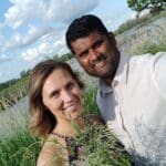 Couple smiling in a field with wildflowers.