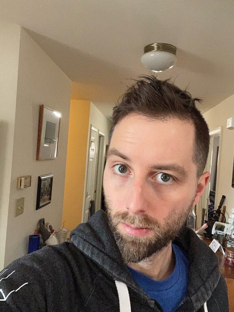 Man with beard and blue shirt in a house.