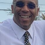 Man smiling in white shirt and tie.