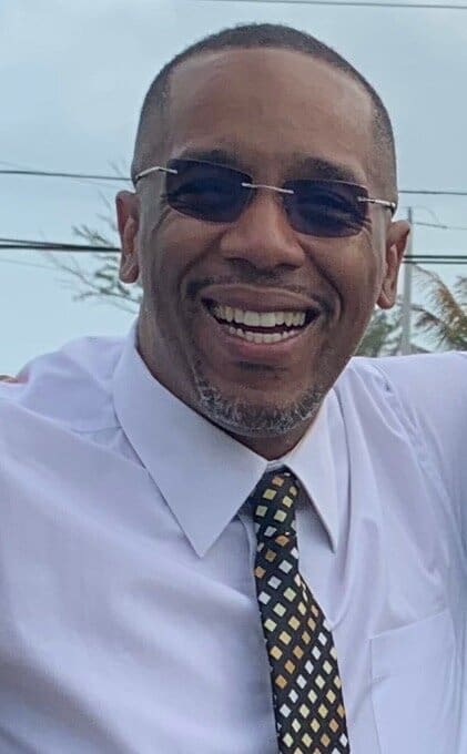 Man smiling in white shirt and tie.