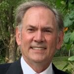 Smiling man in suit and tie outdoors.