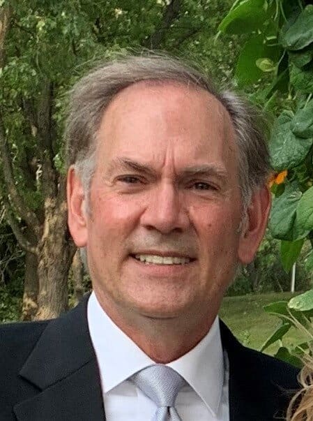 Smiling man in suit and tie outdoors.